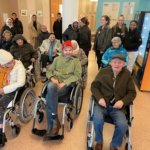 Schüler*innen und Senior*innen im Rollstuhl lachen in die Kamera