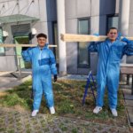 Zwei Schüler halten Holzlatten auf den Schultern
